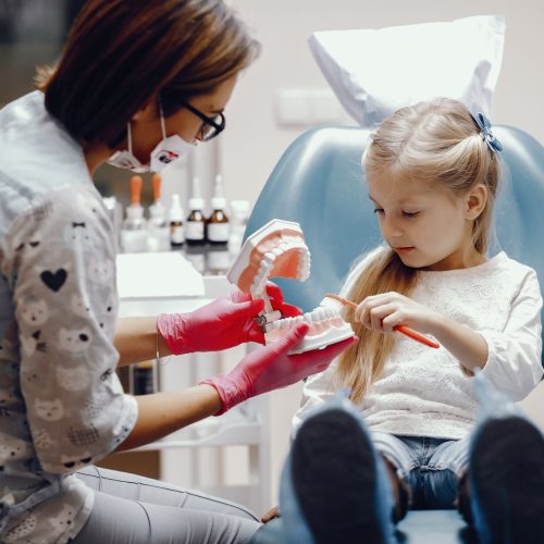 Little girl talking to the dendist. Child in the dentist's office. Woman in a uniform
